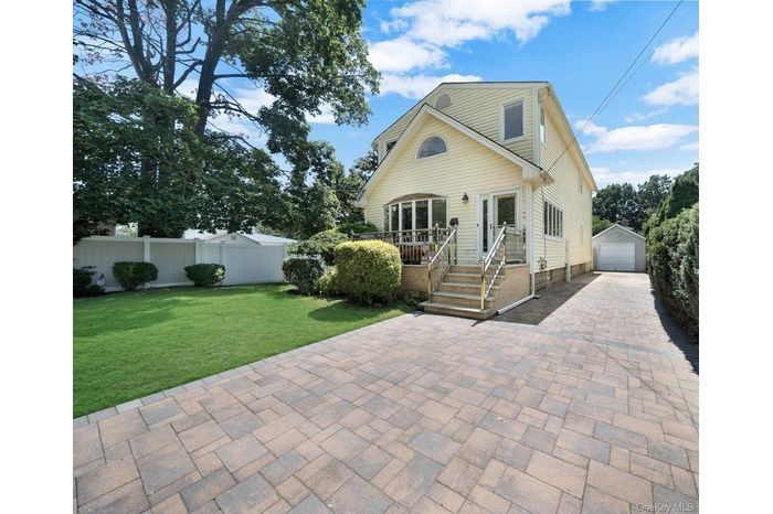 View of front facade with an outbuilding, a garage, a patio area, and driveway