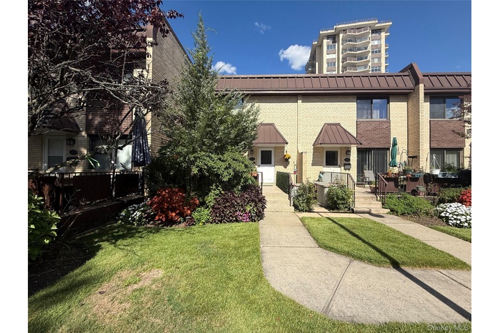 View of front of house with brick siding, a front yard, and a metal roof