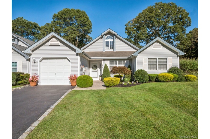 Traditional home with asphalt driveway, a front yard, and an attached garage