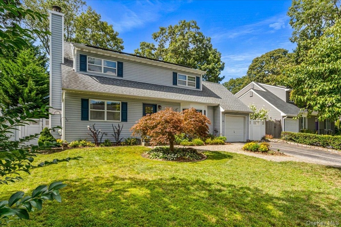 View of front of home featuring a chimney, a garage, driveway, and a shingled roof