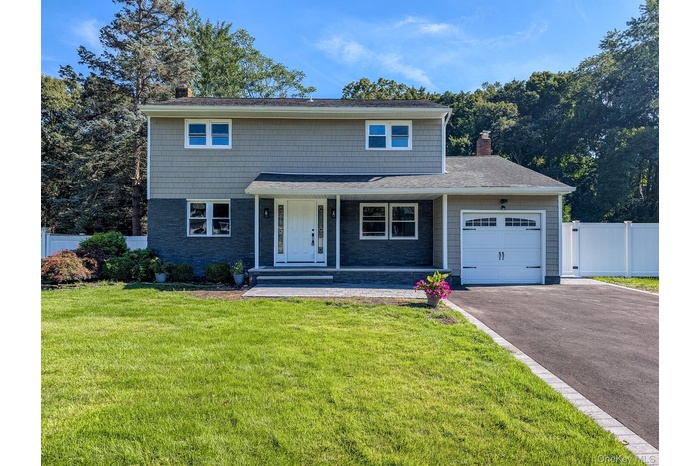 View of front of home featuring a chimney, covered porch, a garage, asphalt driveway, and stone siding