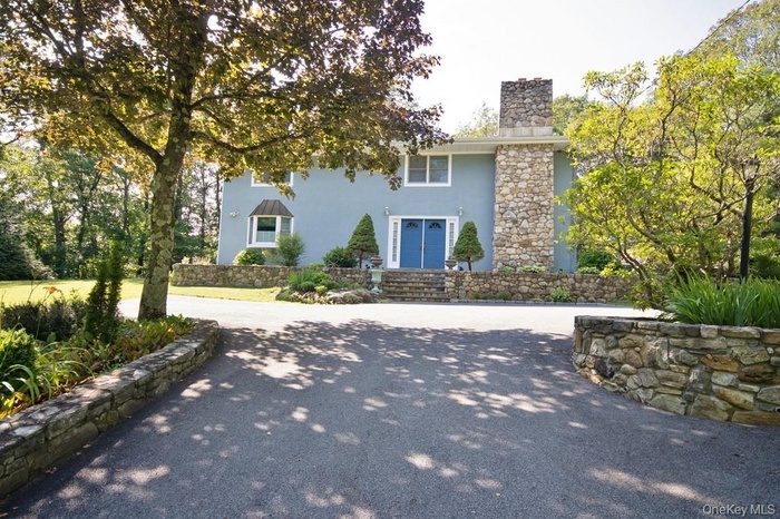 View of front facade featuring stucco siding and a chimney