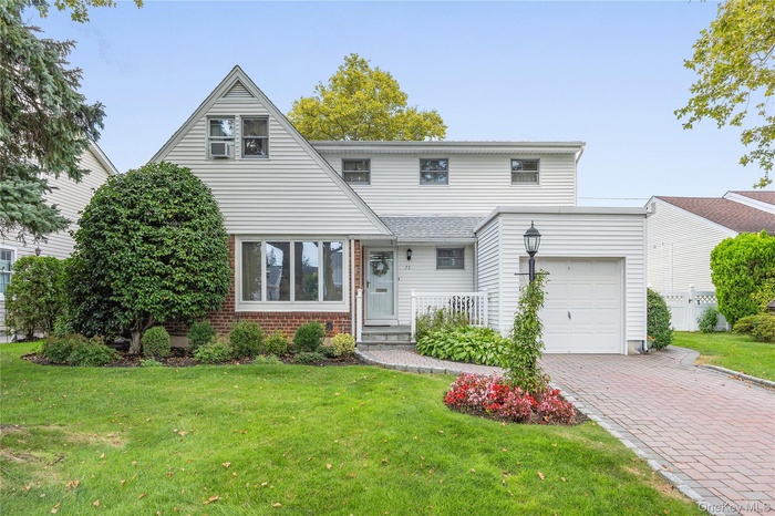 View of front facade featuring a front lawn, brick siding, and a garage