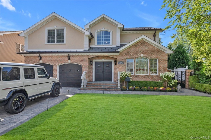 View of front of property with stucco siding, a front lawn, brick siding, and driveway