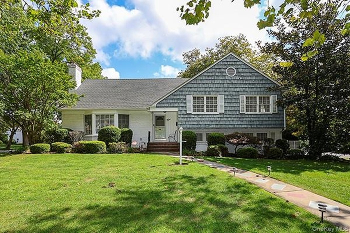 Split level home featuring a front yard and a chimney
