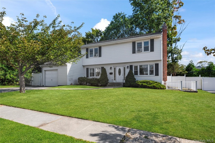 Colonial-style house featuring a chimney and driveway