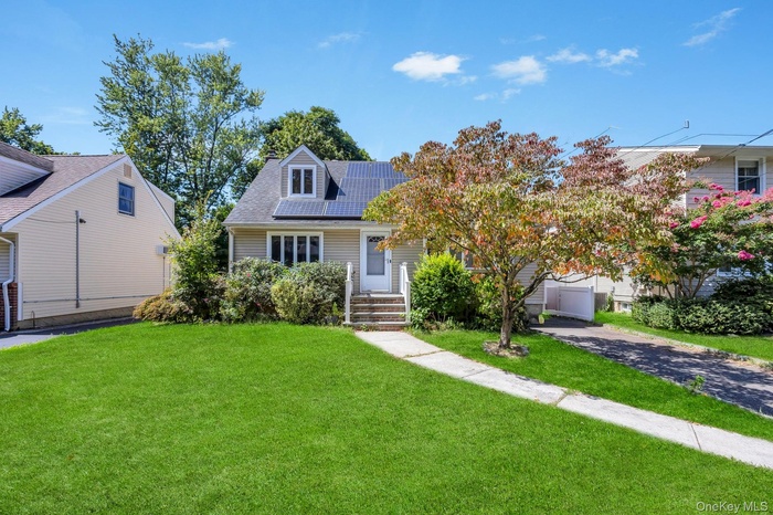 View of front of house featuring a front lawn and roof mounted solar panels
