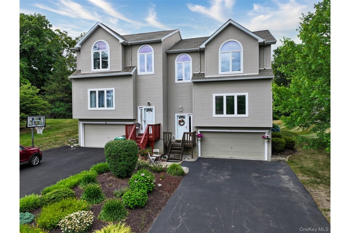 View of front of property featuring a garage, driveway, and a shingled roof