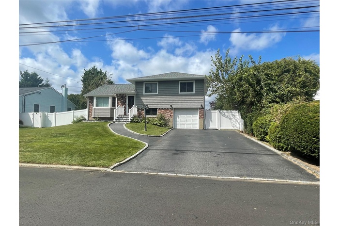 View of front of home with brick siding, asphalt driveway, a gate, and an attached garage