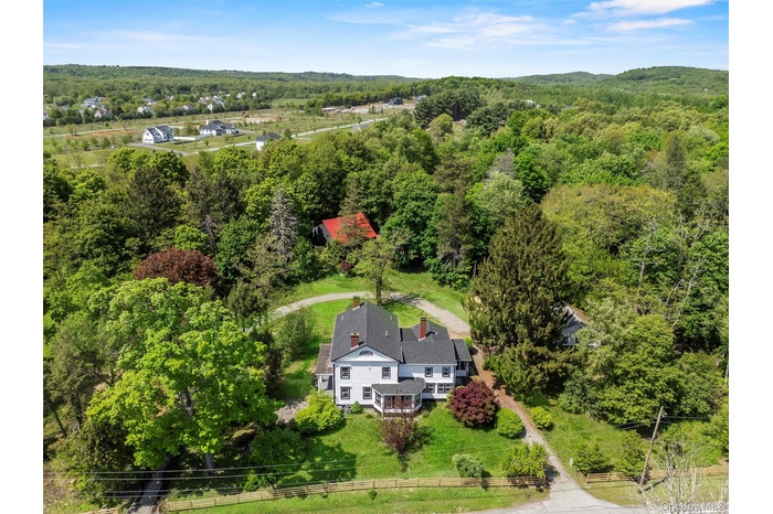 Aerial view of property and surrounding area with a forest