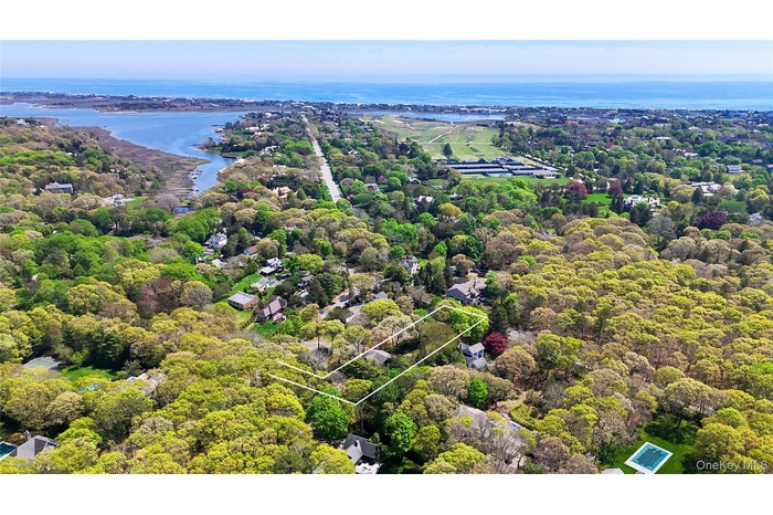 Aerial view of property's location with a nearby body of water, property parcel outlined, and a heavily wooded area
