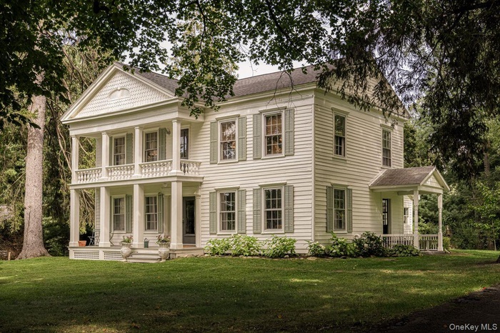 Rear view of house featuring covered porch, a shingled roof, and a lawn