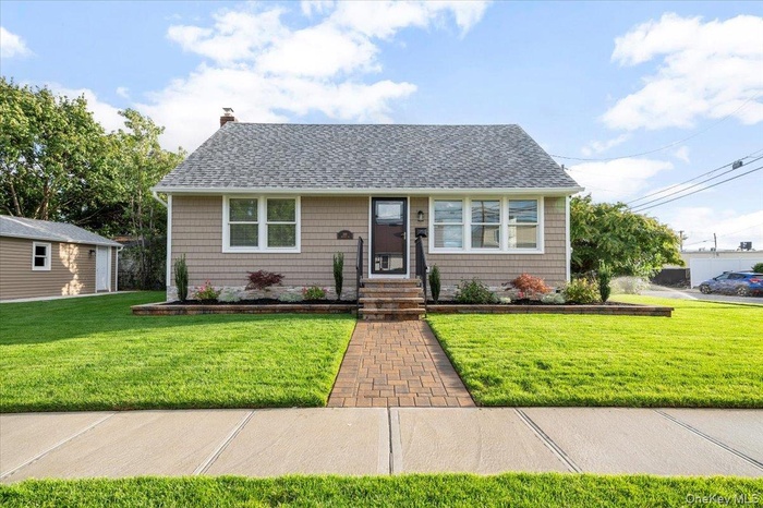 View of front of home featuring roof with shingles, a front yard, and a chimney