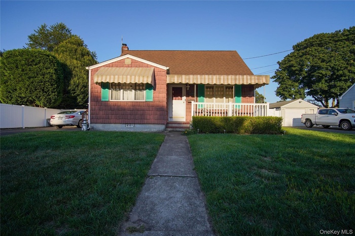 Bungalow-style house with a porch, a front yard, a chimney, and a shingled roof