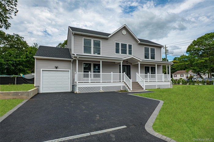 View of front facade with a porch, an attached garage, asphalt driveway, a shingled roof, and a front yard