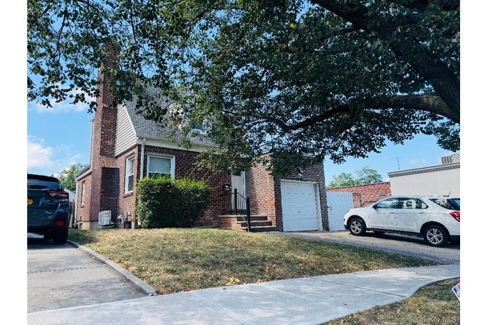 View of front of property with a chimney, brick siding, and a front yard