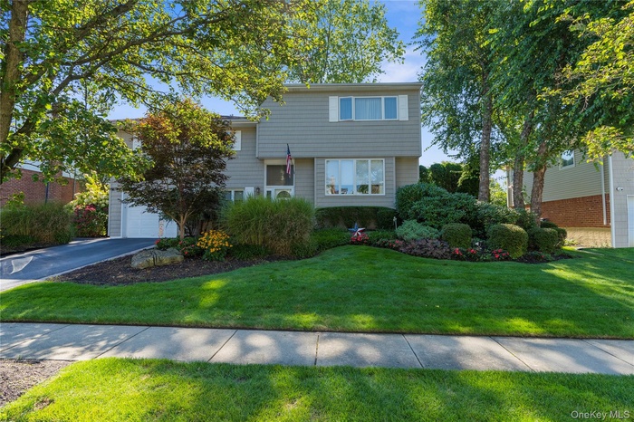 Home featuring a front lawn, a garage, and driveway