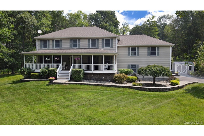View of front of house featuring a shed, covered porch, a front yard, and stairway
