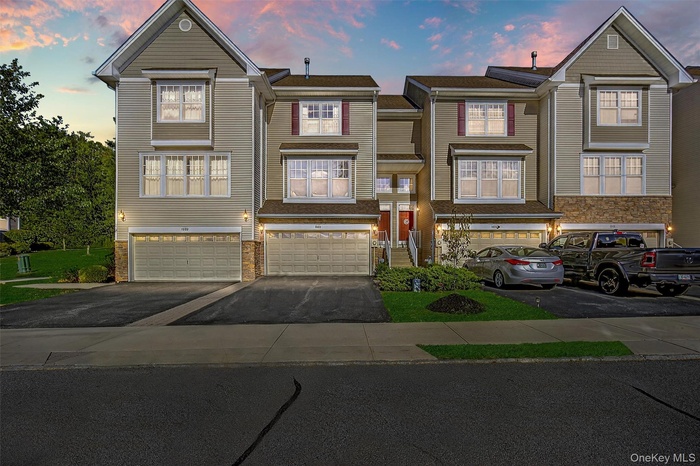 View of front of home featuring driveway, an attached garage, and stone siding