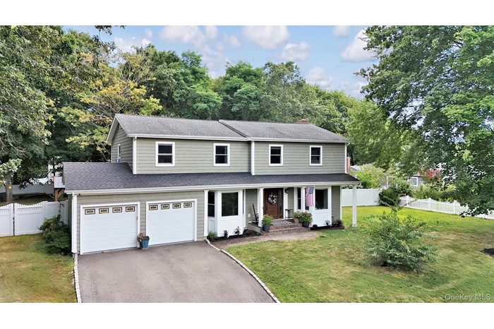 Traditional Colonial home with an asphalt shingled roof, lovely front porch, asphalt driveway, and two-car garage on a beautiful, quiet dead-end stree