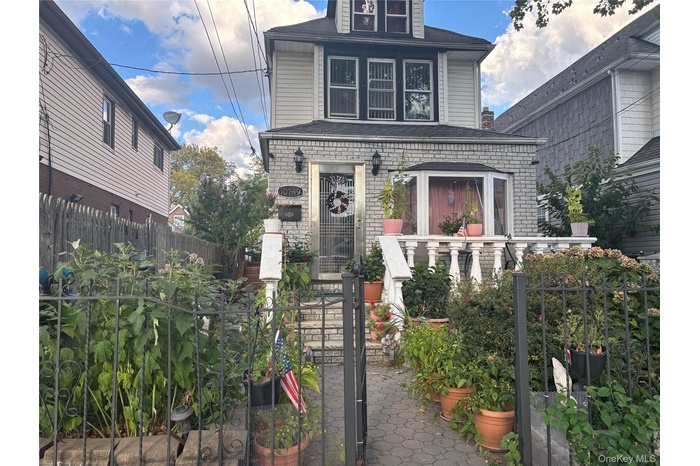View of front of home with a fenced front yard, a gate, brick siding, and a shingled roof