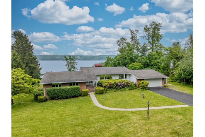 View of front of home with a water view, a front yard, brick siding, an attached garage, and asphalt driveway