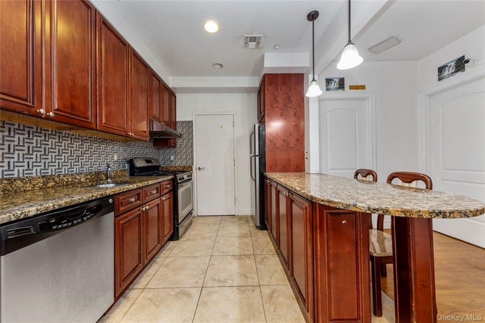 Kitchen with appliances with stainless steel finishes, a kitchen breakfast bar, a sink, dark brown cabinets, and a peninsula