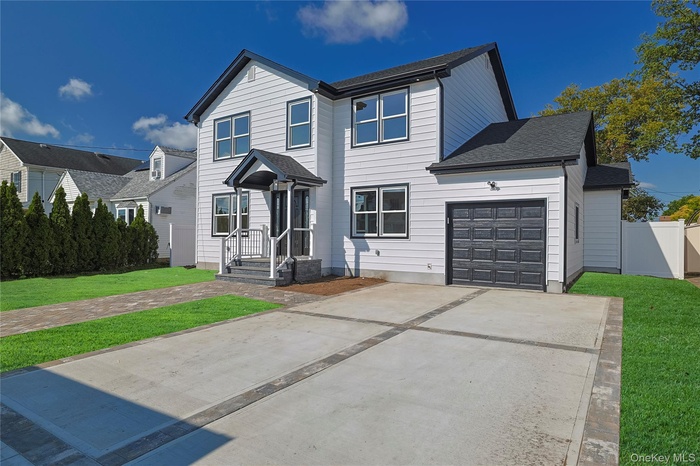 Traditional-style home featuring a front yard, driveway, a shingled roof, and an attached garage