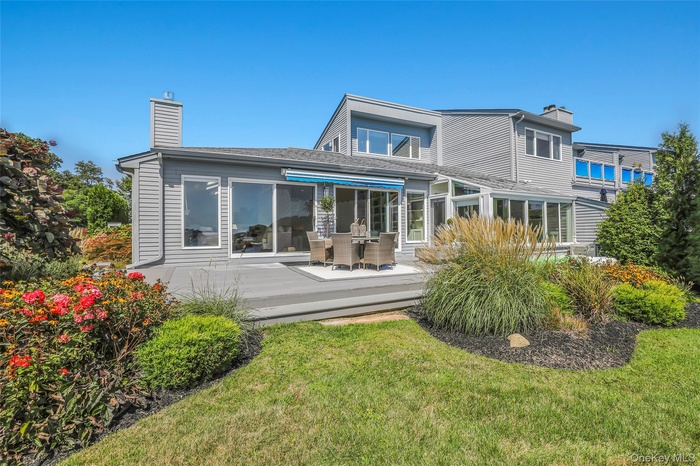 Rear view of property featuring a chimney, a lawn, and a deck