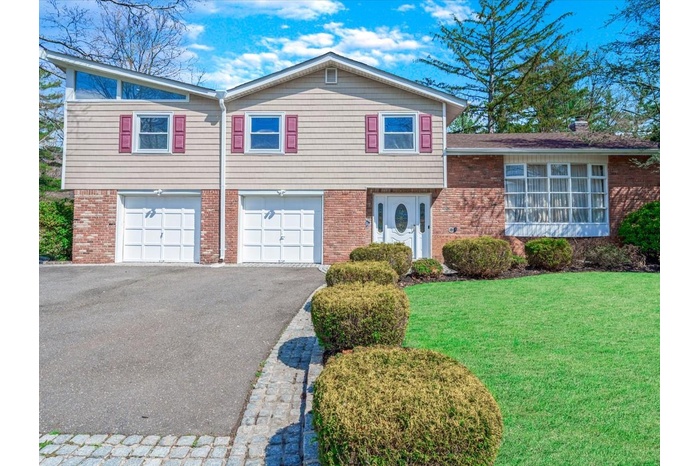 View of front of property featuring a front yard, brick siding, a garage, and aphalt driveway