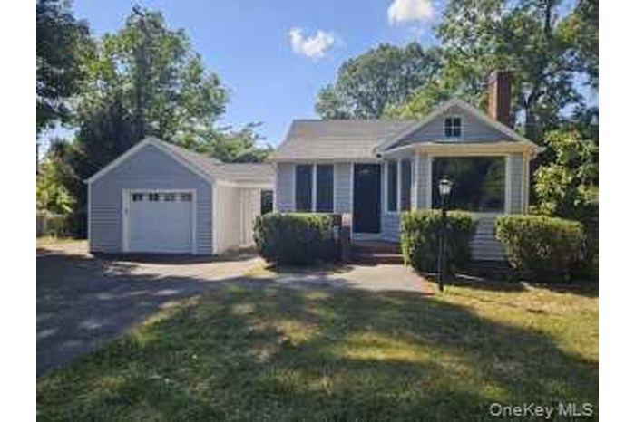 View of front of home with driveway, a garage, a chimney, a front yard, and an outdoor structure