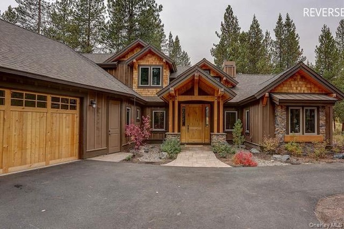 Craftsman-style home with a garage, asphalt driveway, board and batten siding, and roof with shingles