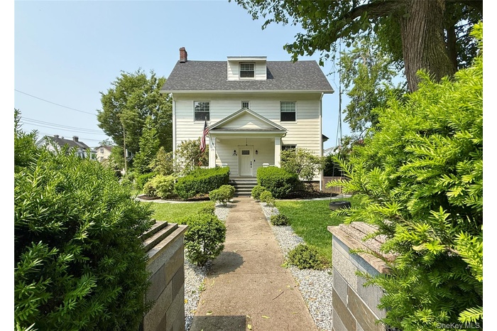 Traditional style home with a chimney and roof with shingles
