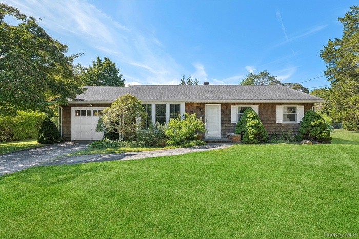 Single story home with asphalt driveway, a front lawn, an attached garage, and a shingled roof