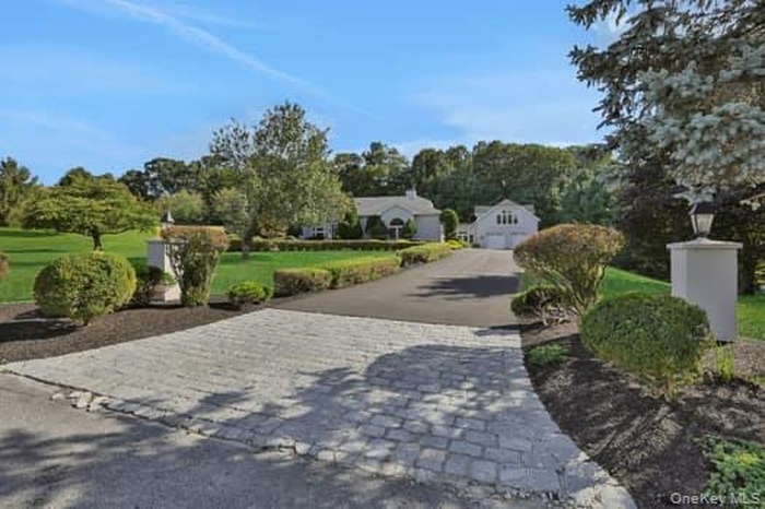 View of community featuring decorative driveway, a yard, and a garage