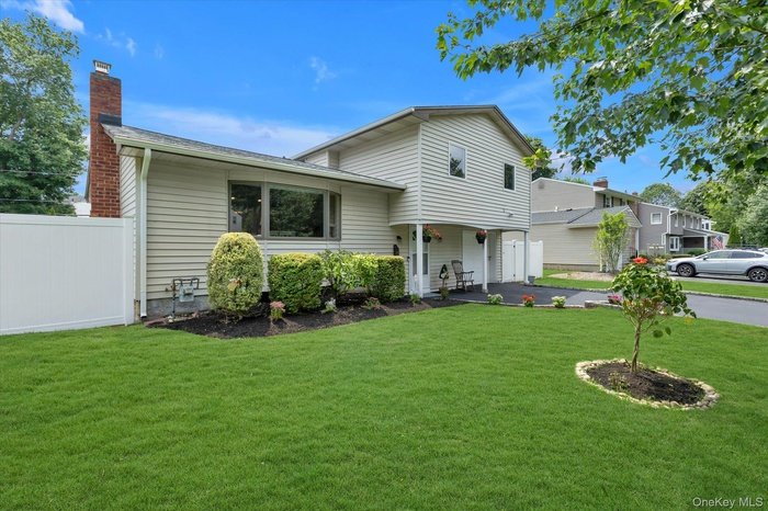 Split level home with covered porch, a chimney, and asphalt driveway