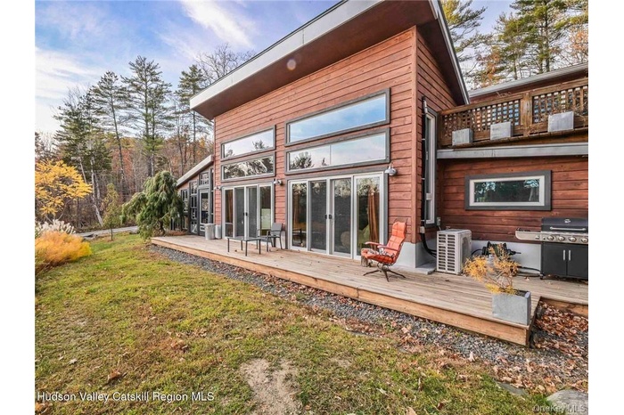 Back of house with a wooden deck and a lawn