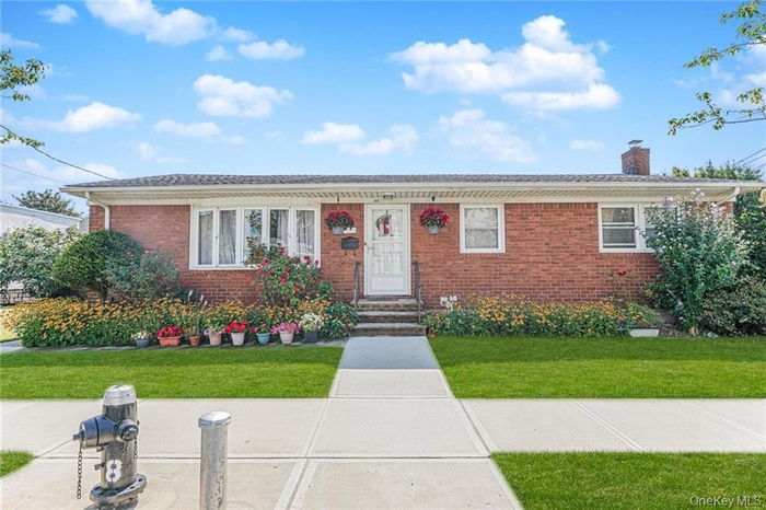 Ranch-style home featuring brick siding, a chimney, a front lawn, and entry steps
