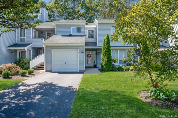 Traditional-style home with a shingled roof, asphalt driveway, a front yard, and a chimney