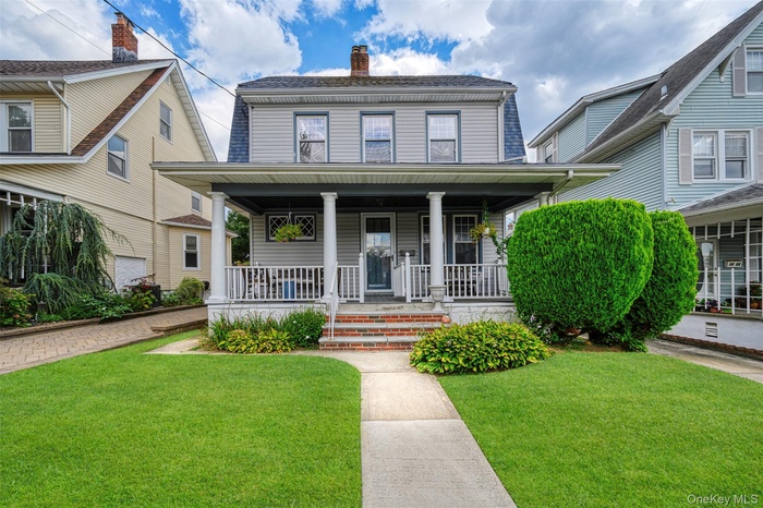 View of front of property featuring a front lawn, covered porch, and a chimney