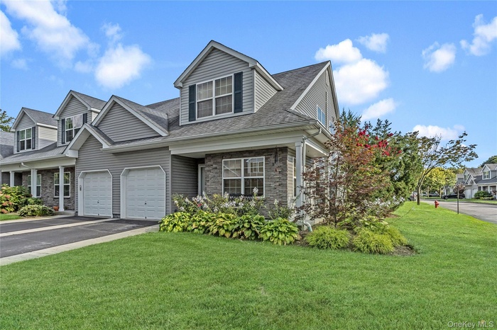 View of front of house with driveway, a front lawn, and stone siding