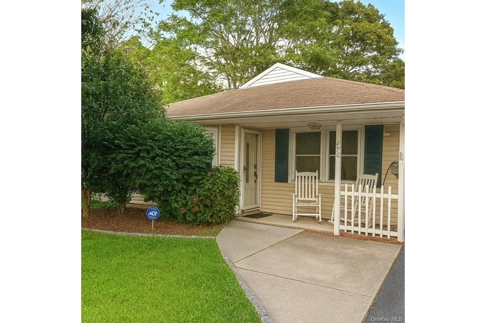 View of front of property with a front yard, roof with shingles, and covered porch