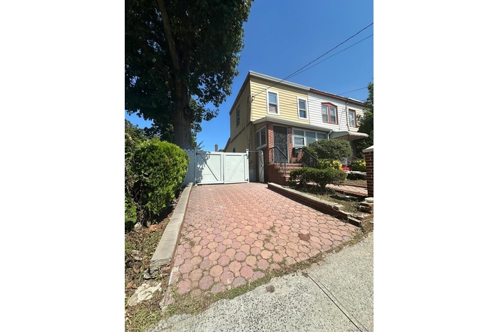 View of side of property with a gate and brick siding