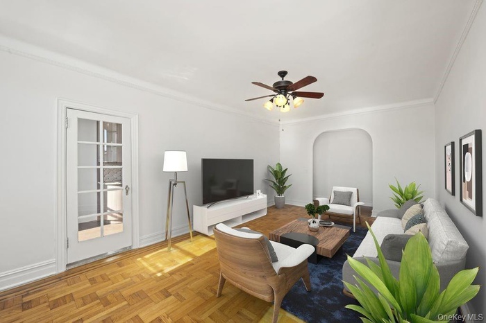 Living area featuring ornamental molding, arched walkways, and ceiling fan