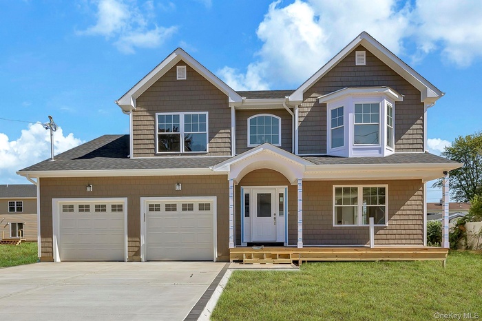 View of front of property featuring a porch, a shingled roof, driveway, and a front lawn
