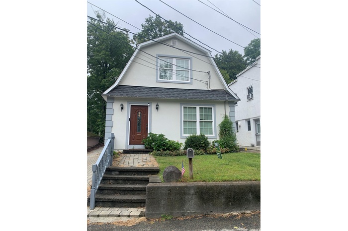 Dutch colonial with a gambrel roof, roof with shingles, stucco siding, and a front yard
