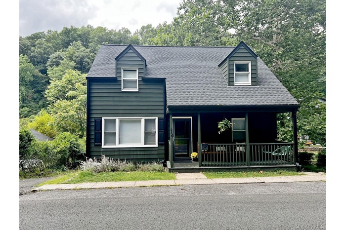 View of front of home featuring covered porch and a shingled roof