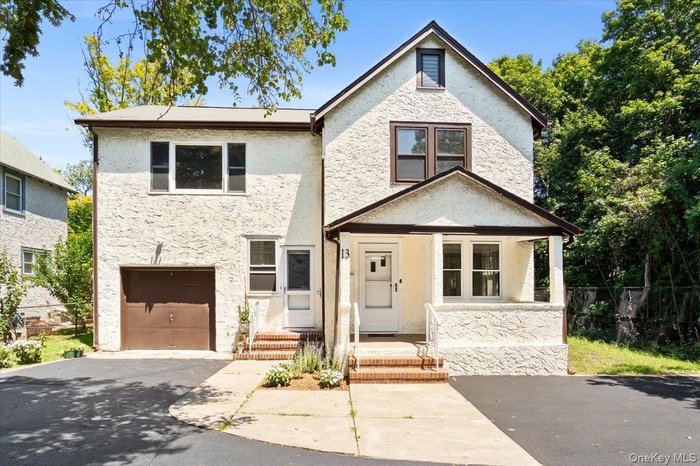View of front of property featuring driveway, an attached garage, and stucco siding