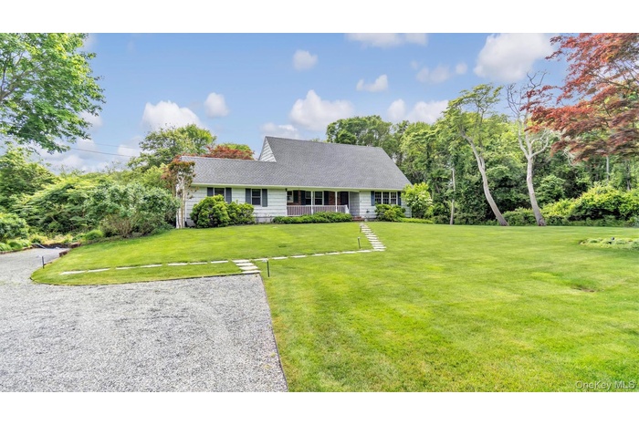 New england style home featuring a front lawn and roof with shingles