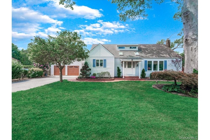 View of front facade with a front lawn, a porch, driveway, a garage, and roof with shingles